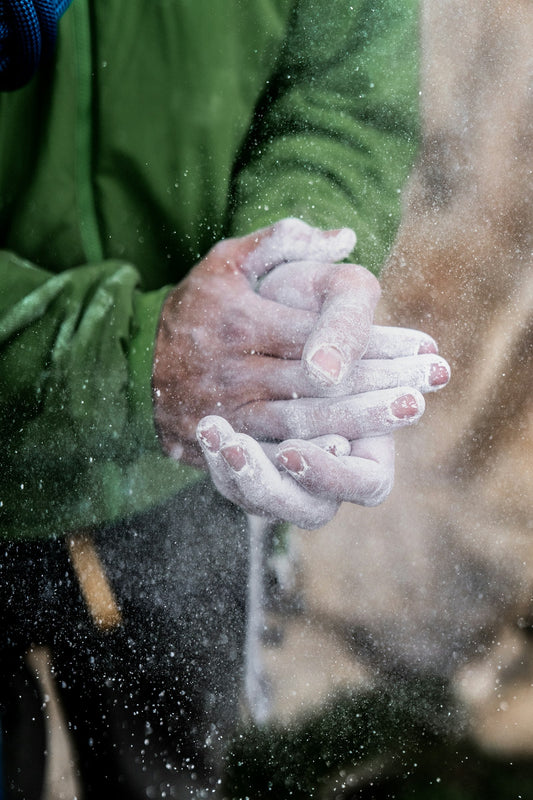 Close-up of a rock climber's chalked hands gripping a hold